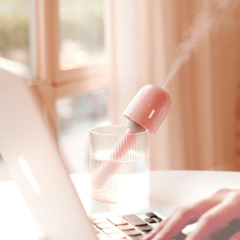 Pink portable mini humidifier in a cup of water